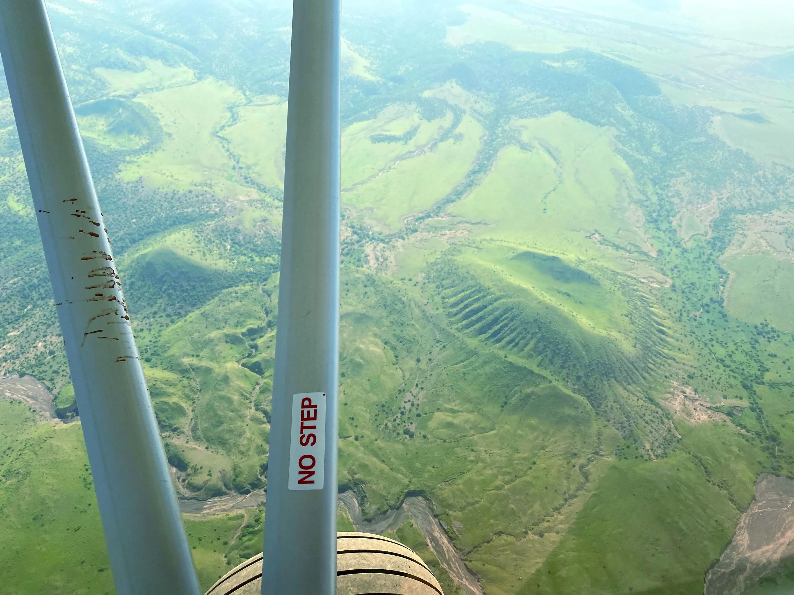 Green crater landscape of the Rift Valley seen past the wing struts of a ZRP aircraft