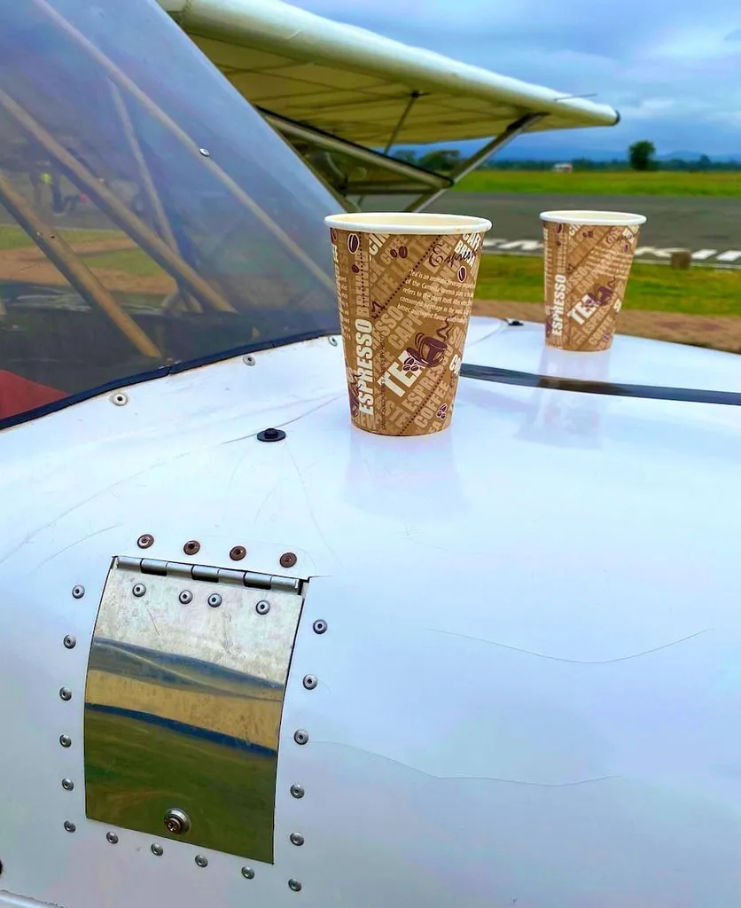 Two coffee cups resting on the engine cowling of a ZRP aircraft between flights